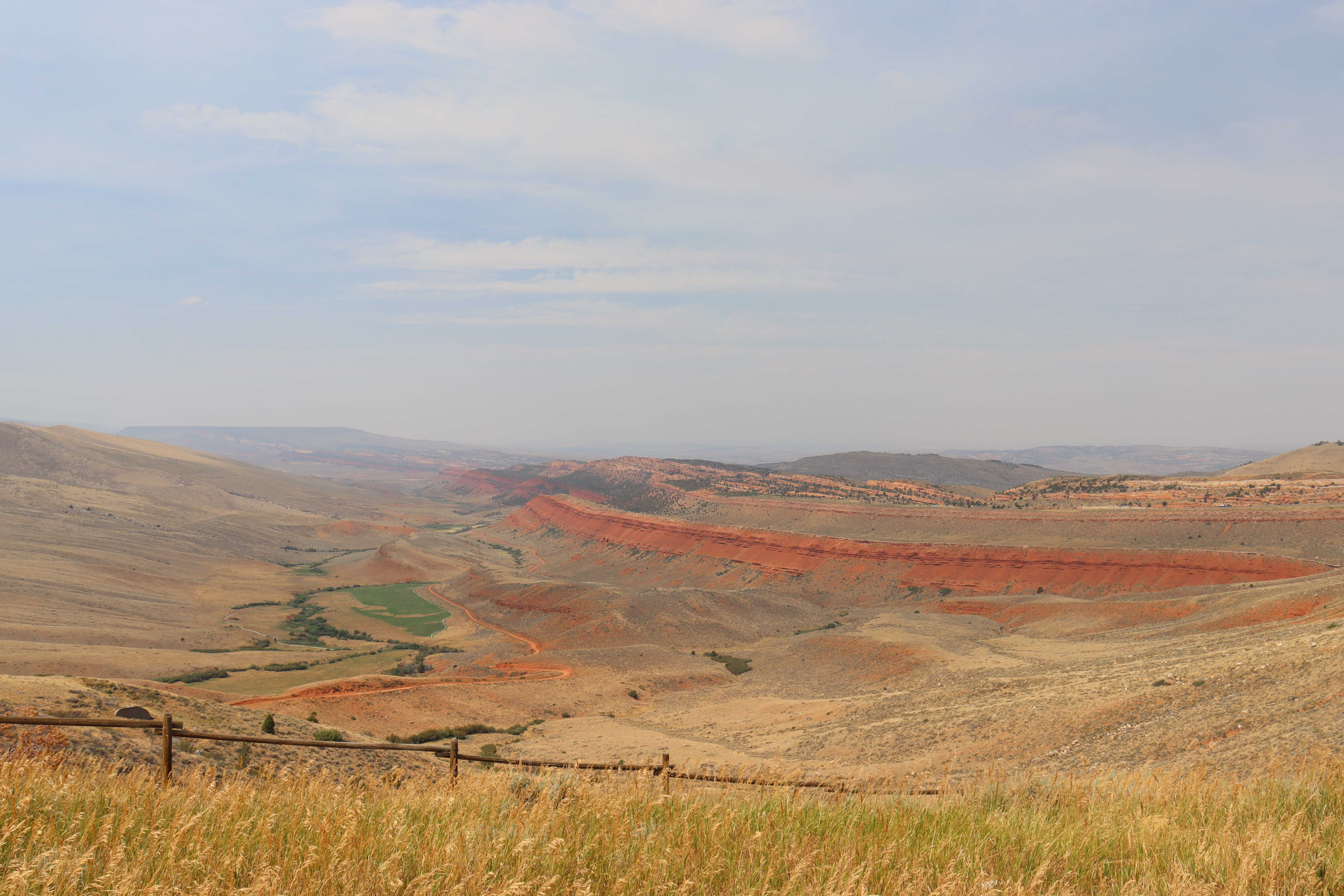A sweeping central Wyoming valley with red-rock ridges and ranch grassland